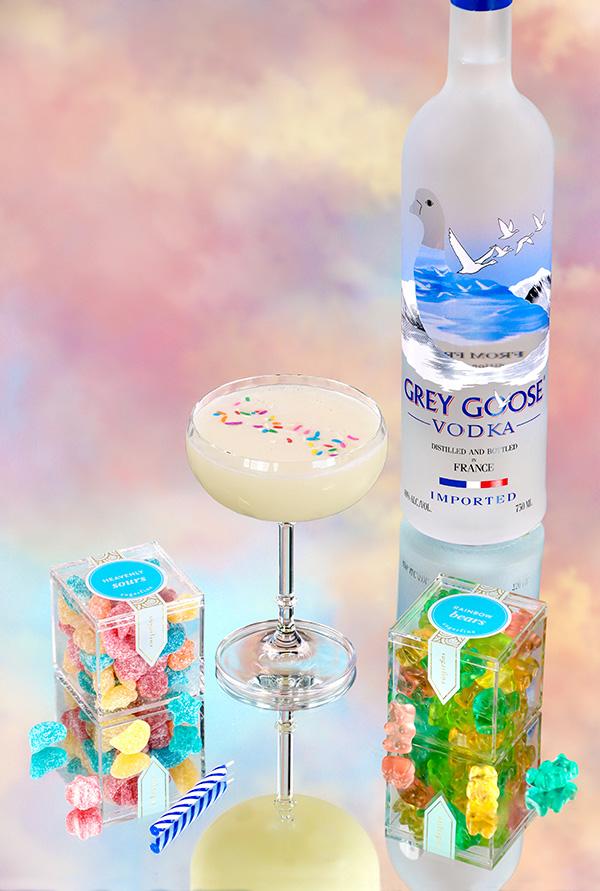 Birthday Cake Cocktail with bottle of Grey Goose Vodka and Gummy Bears With Dreamy Background.